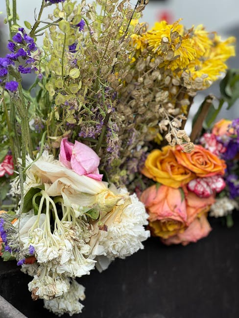 A close-up of a mixed bouquet of fresh flowers with various colors and textures, including white, pink, orange, and purple blooms. The arrangement features roses, carnations, and other small flowering